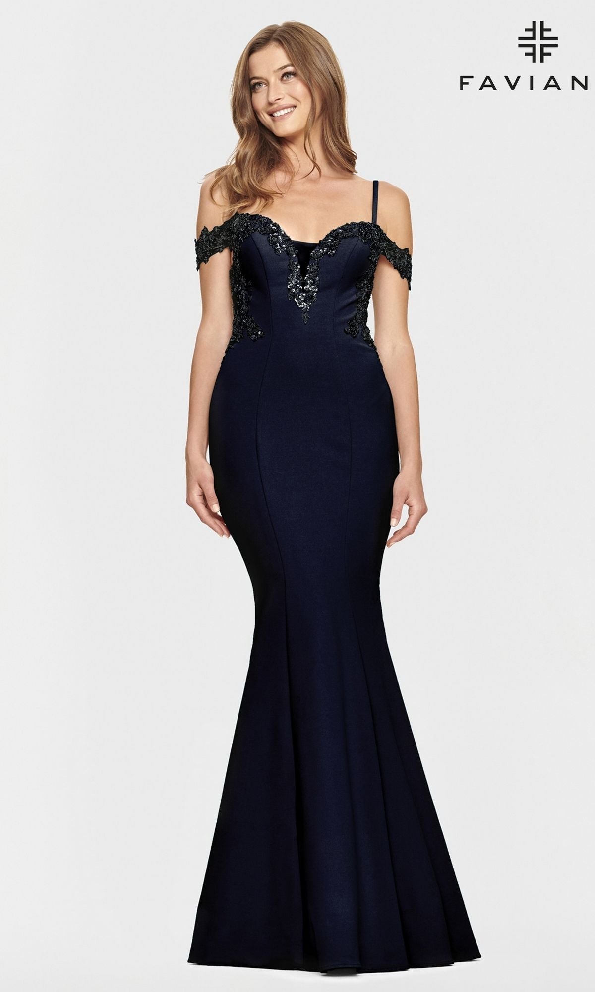 A woman stands against a plain light background wearing the Faviana Cold-Shoulder Navy Blue Prom Dress S10866, a fitted mermaid gown with black lace accents. The Faviana logo appears in the top right corner.
